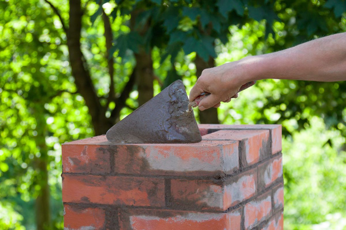 Mason repairing brickwork on a chimney in Alhambra, California