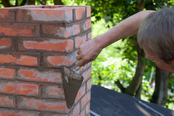Mason repointing chimney mortar joints with a trowel in Alhambra